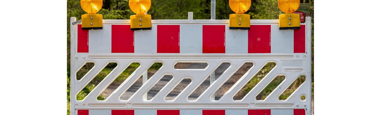 weiße Absperrung mit orangenen Signalleuchten