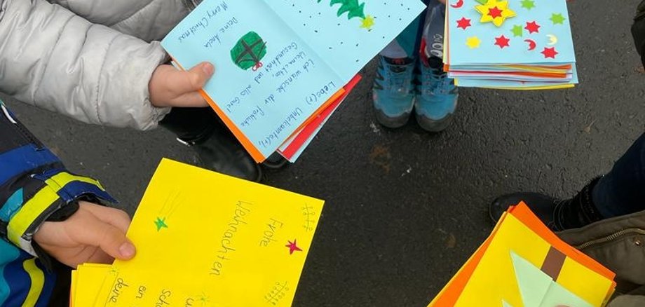 Kinder zeigen selbst geschriebene Weihnachtskarten