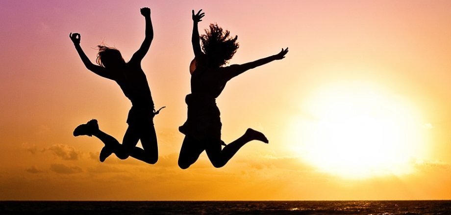 Zwei springende Jugendliche im Sonnenuntergang